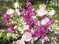Purple, white and pink orchids and roses. Outdoor area wedding decor.