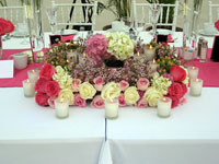 Large square centerpiece in pink of roses and candles.