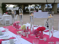 Table centerpieces at outdoor Maui wedding reception. Floating candles in trumpet vases.