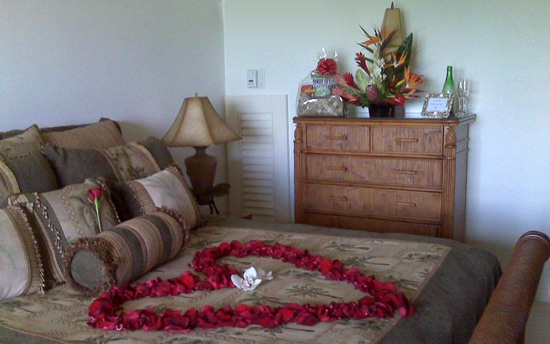 Maui Honeymoon Special. Rose petal heart on bed, tropical arrangment and munchies gift basket